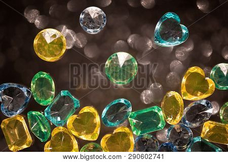 Shiny Yellow, Green And Blue Glass, Jewelry, Placers On A Black Background With Blurred Spots.