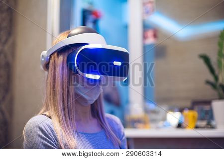 A Young Blond Caucasian Sick Girl Covers Her Face And Wears A Virtual Reality Headset Enjoys Virtual