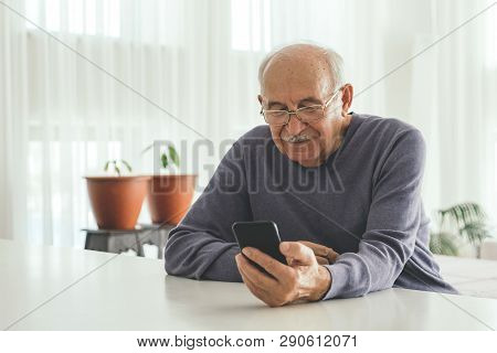 Old Retired Pensioner In Glasses With White Hair Sits Infront Of The Computer And Serf Web-sites At 