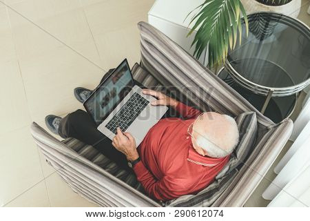 Old Retired Pensioner In Glasses With White Hair Sits Infront Of The Computer And Serf Web-sites At 