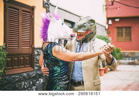 Crazy Couple Dancing And Wearing Dinosaur T-rex And Unicorn Mask - Senior Elegant People Having Fun 