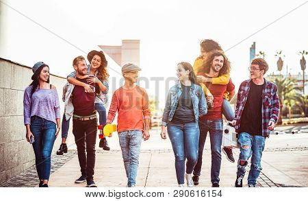 Group Of Happy Friends Having Fun Outdoor - Young People Piggybacking While Laughing And Walking Tog