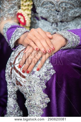Woman Waiting With Her Hand On Knee. She Is Wearing Traditional Javanese Wedding Dress With Red Nail