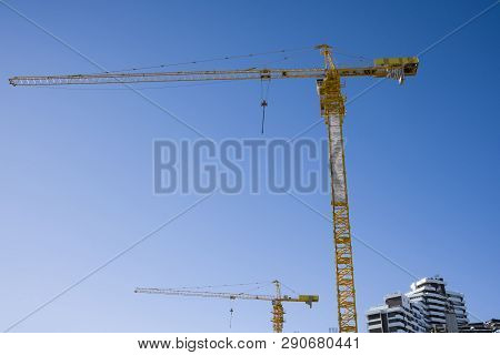 Multi-storey Construction. Two Taps On Blue Sky Background. In The Background Is An Unfinished Build