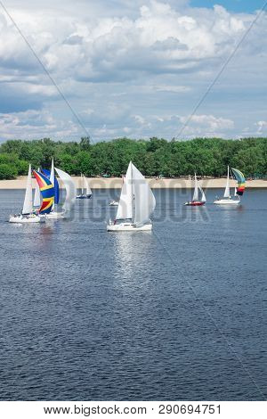 Regatta Competition Of Lake River Sailing Yachts Boats With White Sails, Reflected Sky Clouds In Wat