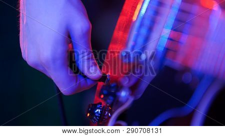 Young Musician Playing Guitar In Neon Lighting. Plugging In The Plug