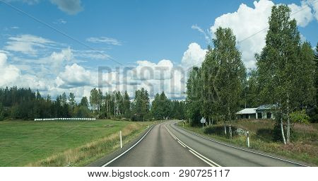 Road In Finland. Blue Sky And White Clouds