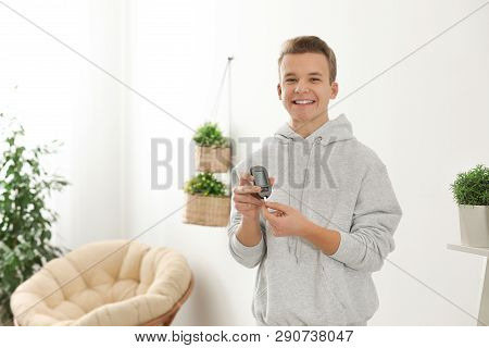 Teen Boy Holding Digital Glucometer At Home. Diabetes Control
