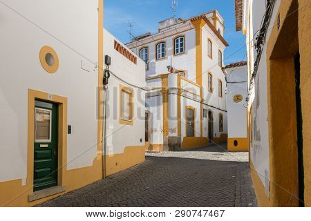 The View Of Narrow Paved Street Of Evora With The Cozy White Houses. Evora. Alentejo. Portugal