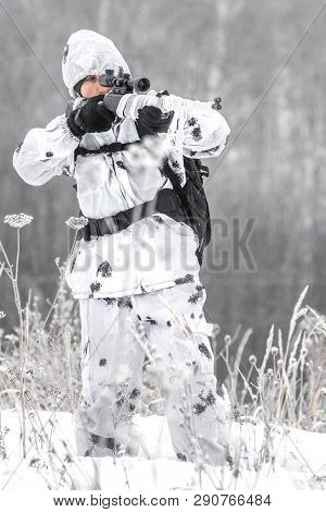 Man Soldier In The Winter On A Hunt With A Sniper Rifle In White Winter Camouflage Aiming Standing I