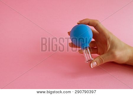 Female Hand With French Manicure Holds Blue Cosmetic Medical Jar For Vacuum Facial Massage On Pink B