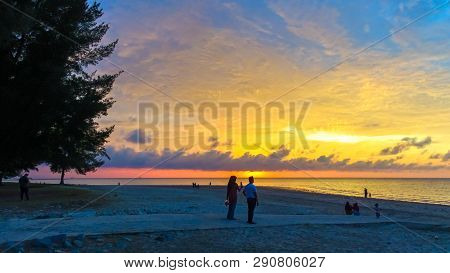 A Group Of People Gather To Watch The Sunset At Layang Layangan Beach In Labuan,malaysia.it Is A Fab