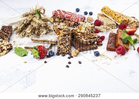 Assortment Of Different Granola Cereal Bars On White Stone Background. Healthy Pre Or Post Workout S