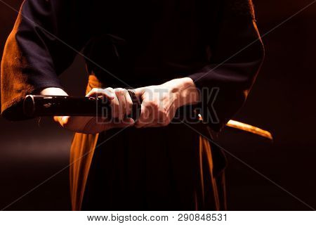 Partial View Of Kendo Fighter Holding Bambo Sword On Black