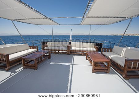 Rear Sundeck Of A Large Luxury Motor Yacht With Chairs Sofa Table And Tropical Sea View Background