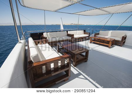 Rear Sundeck Of A Large Luxury Motor Yacht With Chairs Sofa Table And Tropical Sea View Background