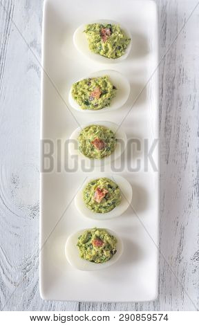 Guacamole And Bacon Deviled Eggs On The White Plate