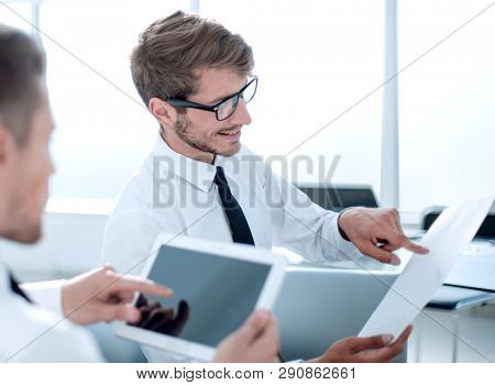 Team of two businessmen discussing new project using tablet and dokuments in the office.