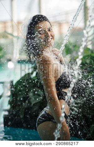 Sexy Slim Female In Swimsuit Takes Shower In Swimming Pool Between Green Bushes On Rooftop With City