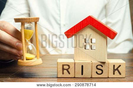 Wooden Blocks With The Word Risk, The House And The Clock. The Concept Of Non-payment Of Interest Ra