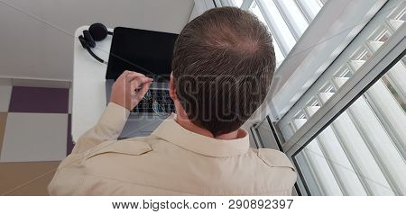 Rear View Of A Man Wearing Official Collar Shirt Sitting Near Window Holding Eyeglasses In Left Hand