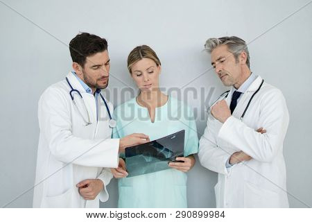 Doctors and nurse looking at x-ray on grey background