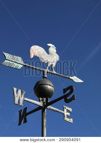 Old Wind Vane With Cock On Top And Cardinal Points On The Sky
