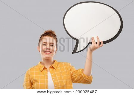 people concept - smiling red haired teenage girl in checkered shirt holding blank speech bubble over grey background