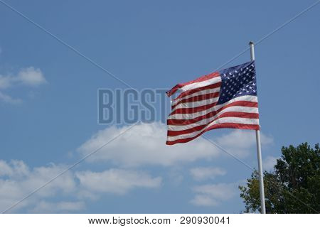 Here Is The American Flag Blowing In The Wind. The Flag Has Been Blown Around The Flag Pole And Stil