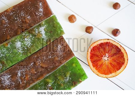 Half A Red Orange, Oriental Delicacy - Sudzhuk And Hazelnuts On A White Surface Of Painted Boards. D
