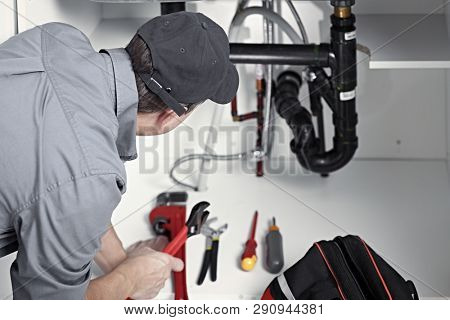 Plumber repairs a sink.