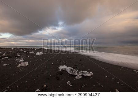 Dramatic A Sunset With Amazing Transparent Blue Iceberg Pieces On Diamond Beach With Black Sand Near