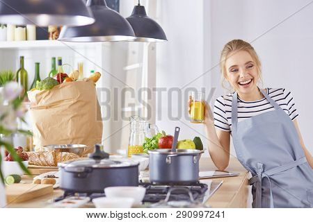 The Girl At The Table In The Kitchen With A Glass Of Orange Jui