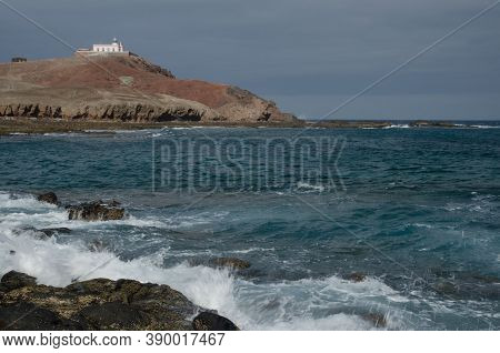 Coastal Landscape And Arinaga Lighthouse In The Background.