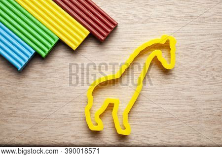 Plasticine Of Different Colors Lies On A Wooden Substrate With Molds For Modeling