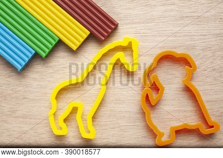 Plasticine Of Different Colors Lies On A Wooden Substrate With Molds For Modeling