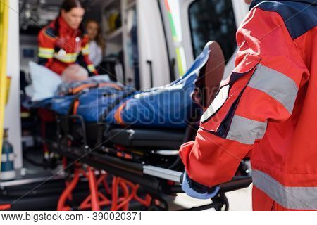 Focus Of Paramedic In Uniform Carrying Stretcher With Patient In Ambulance Ca Outdoors