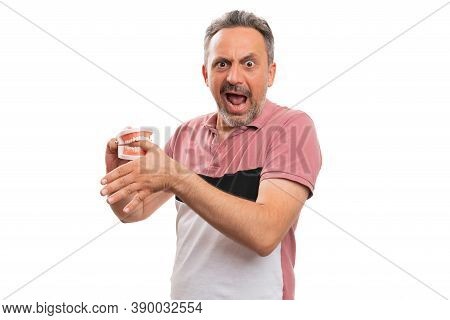 Fake Teeth Denture Prothesis Biting Thumb Finger Of Adult Male Model Making Hurt Expression With Bla