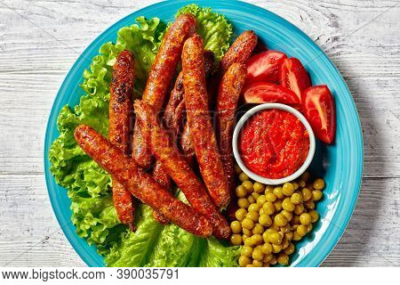Short Italian Pork Sausages Chipolata Grilled And Served On A Blue Plate With Tomato Ketchup And Che