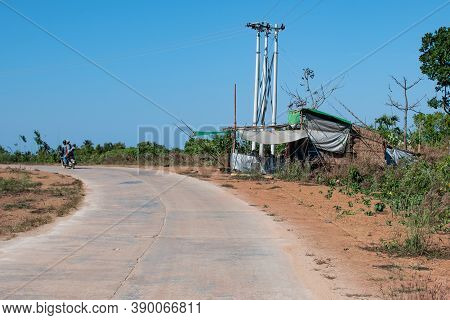 Chaung Thar, Myanmar - December 26, 2019: People Drives Motorbikes Past A Street Restaurant On A Rur