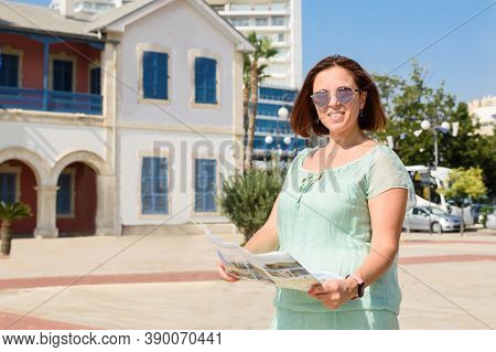 Portrait Of A Young Smiling Caucasian Brunette Woman In Green Dress And Stylish Sun Flasses At The B