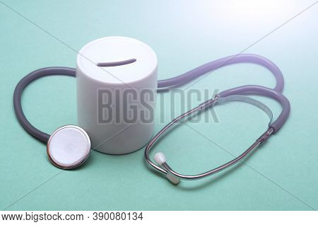 Cost Of Healthcare. Money Box With A Medical Doctors Stethoscope On Green Background