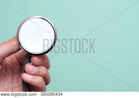 Female Hand Holds A Stethoscope On A Blue Background. Concept Doctor, Doctors Appointment, Virus, Tr