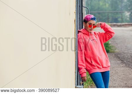 Portrait Of A Young Girl With Short Colorful Hair And Nose Piercing Satanding Near The Wall With Woo