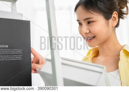 Student Woman Asian Holding A Book In Her Hand And Is Selecting A Treatise From The Shelf To Read.