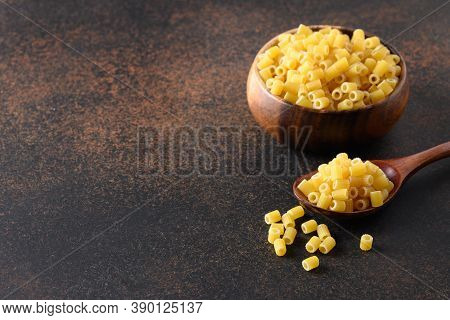 Ditalini Pasta In Wooden Bowl On Brown Table. Close Up. Copy Space.