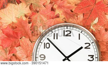 Plain Wall Clock In The Center Of Autumn Orange Red Leaves And Fall Foliage. Two Oclock. Copy Space,