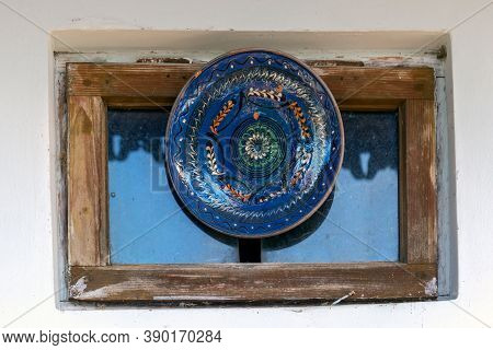 Romanian Traditional Ceramic Plate From Horezu Area, Romania, Placed Ornamentally On A Rustic House 