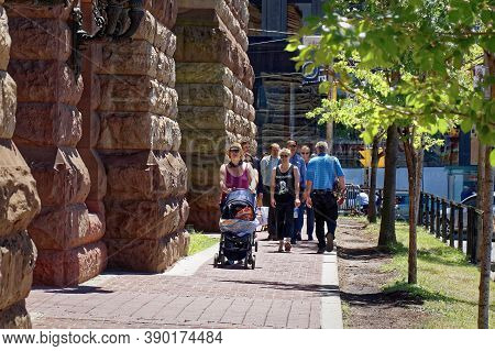 Toronto, Canada - 06 27 2016: People Stroding Along The Sidewalk With Green Young Trees Beside The S