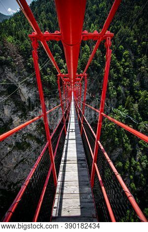 Wooden Long Footbridge Above The Deep Gorge With A River Beach At The Bottom, Between The Rocks. Wil